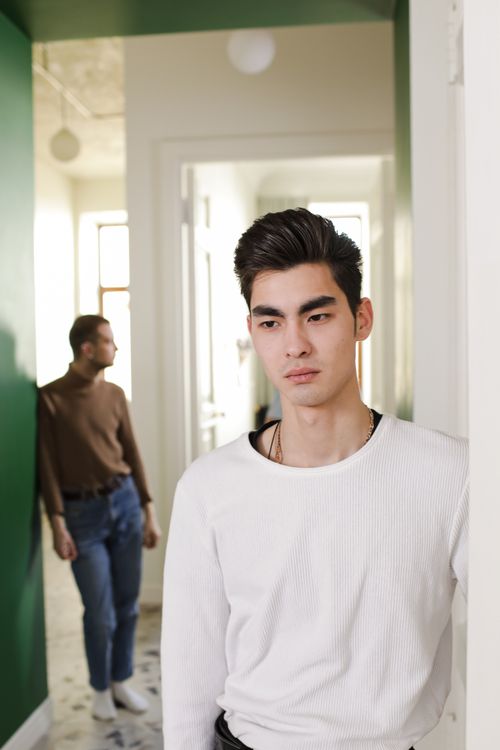 Free Young adults standing indoors with natural light creating a thoughtful atmosphere. Stock Photo