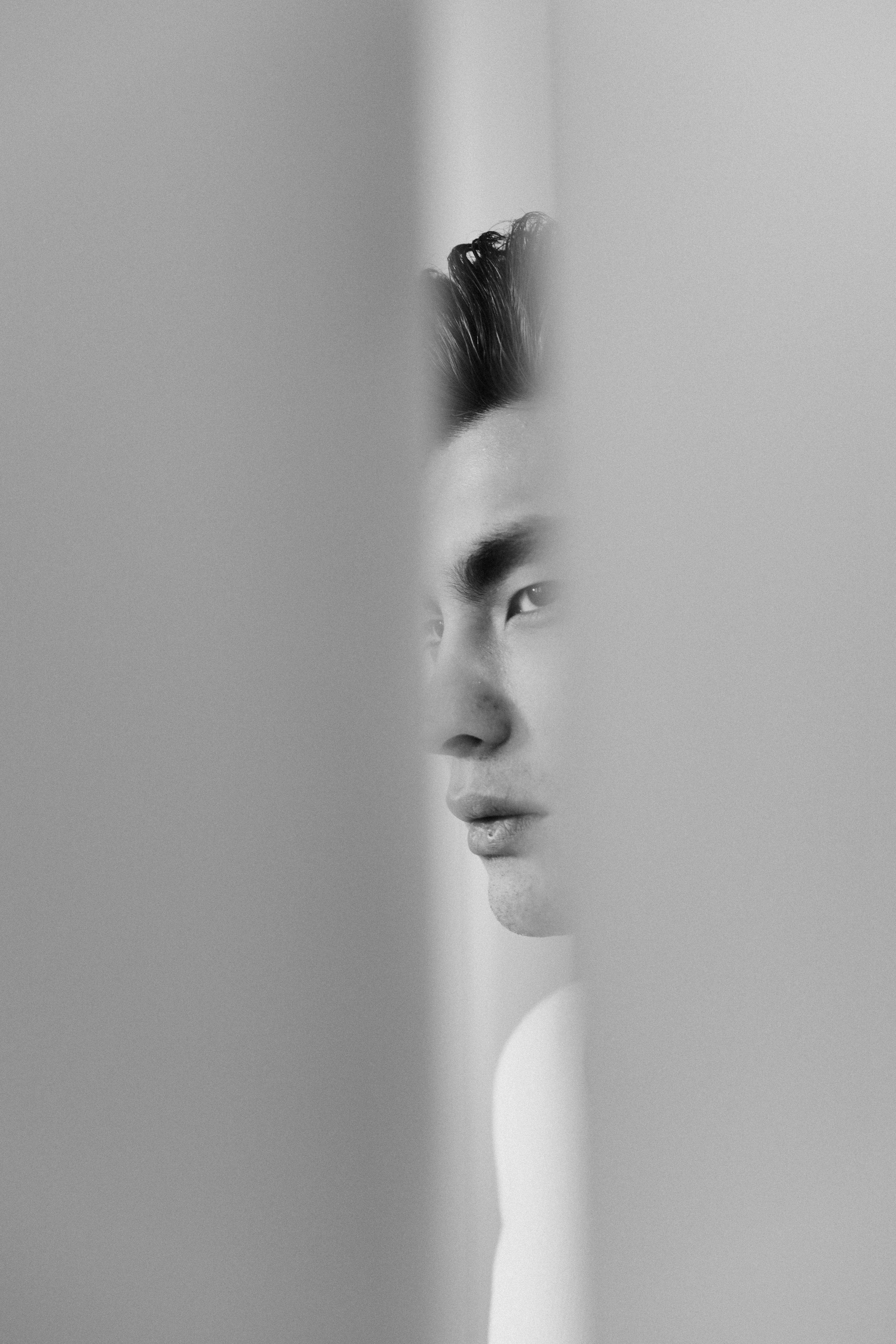 Monochrome side portrait of an adult man through vertical slits, conveying contemplation.