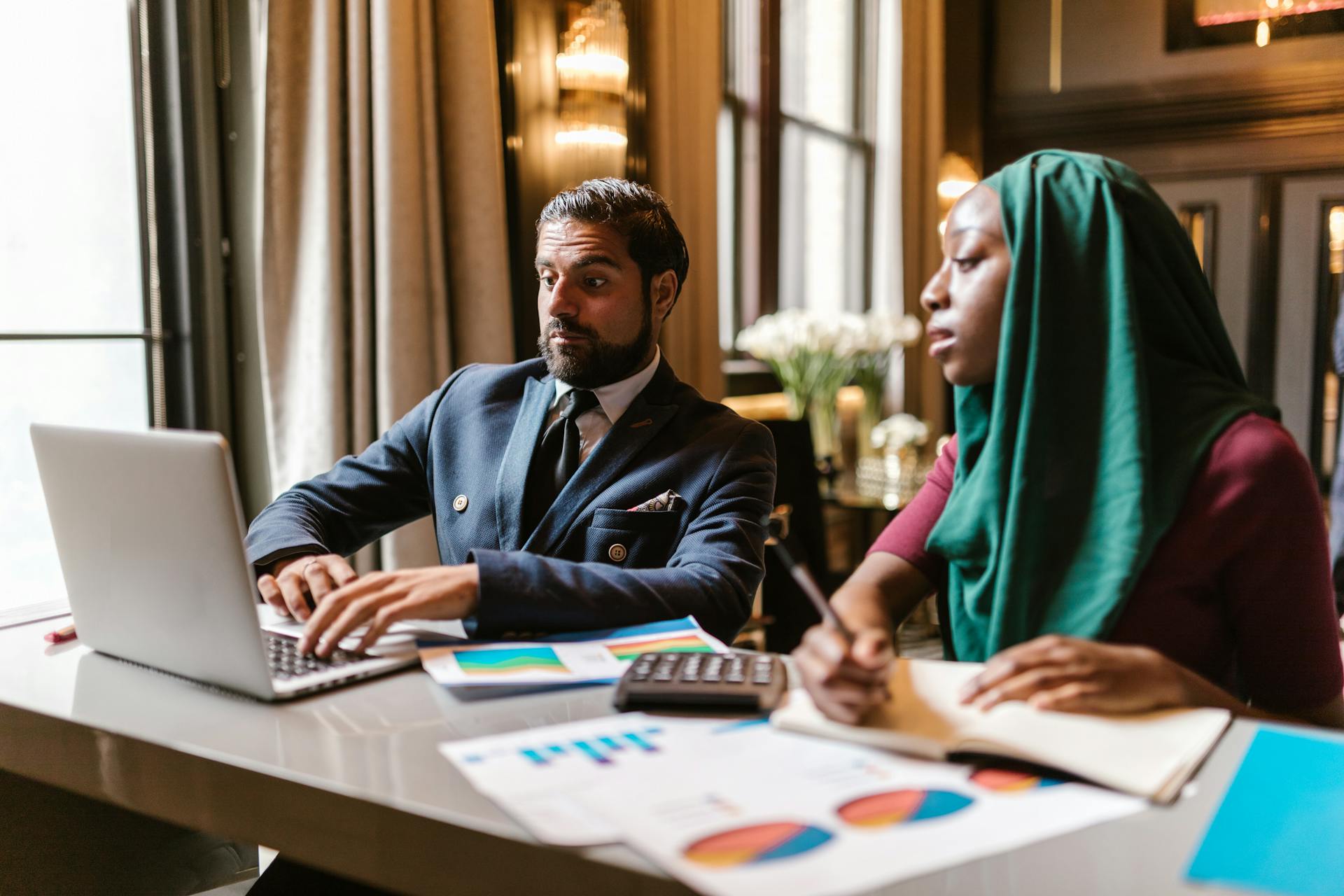 Man and Woman Looking at Laptop Screen in Office