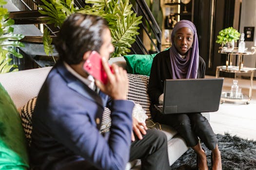 Business professionals with laptop and phone collaborating in a modern office setting.