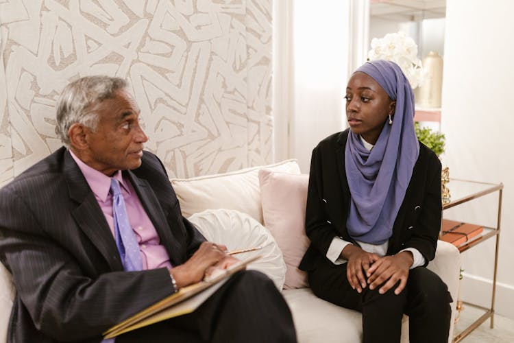 A Man And Woman Sitting On The Couch While Having Conversation