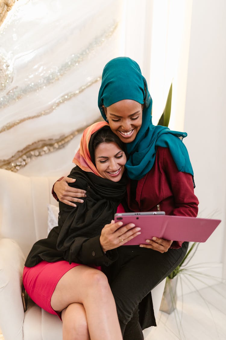 Women In Hijab Smiling While Looking At An IPad