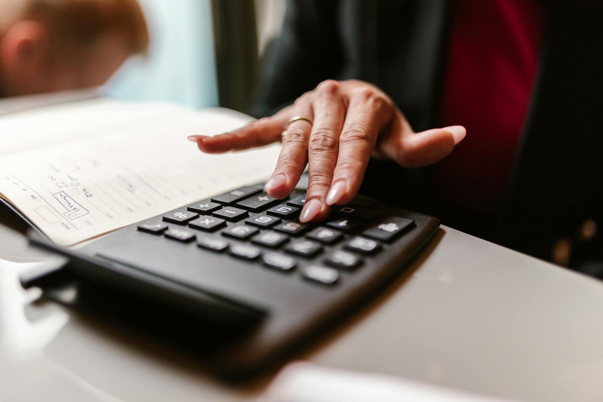 A Person Using Calculator on the Table