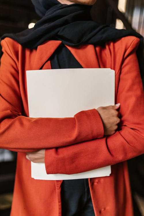 A Person in Orange Blazer Holding a White Folder