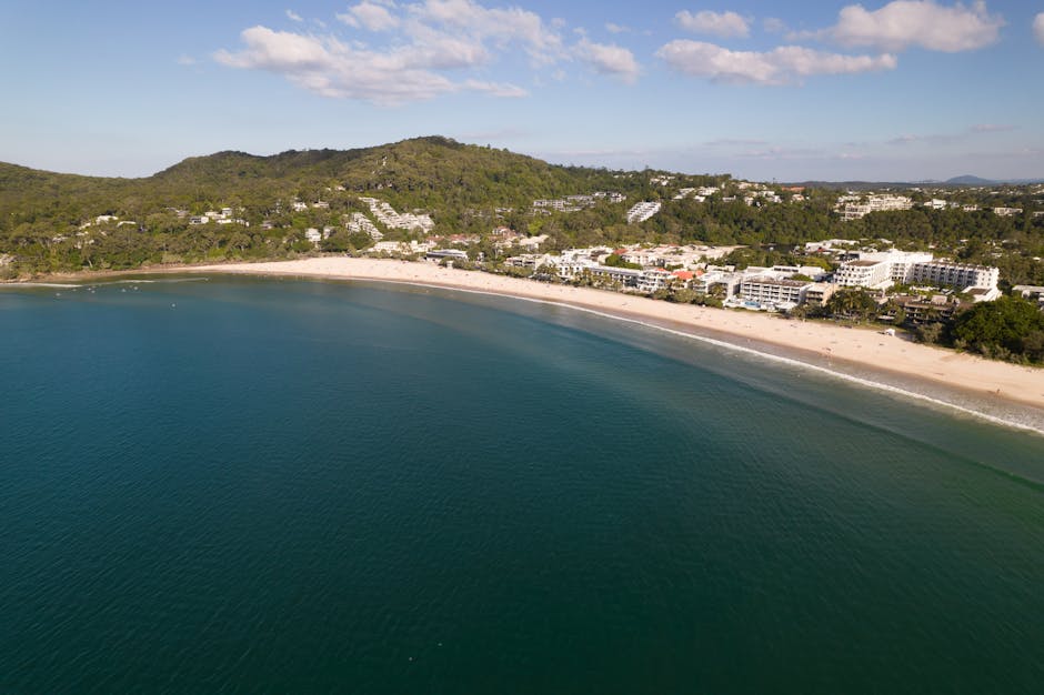 Stunning aerial view of Noosa Heads beach and coastline, showcasing lush greenery and clear blue waters.