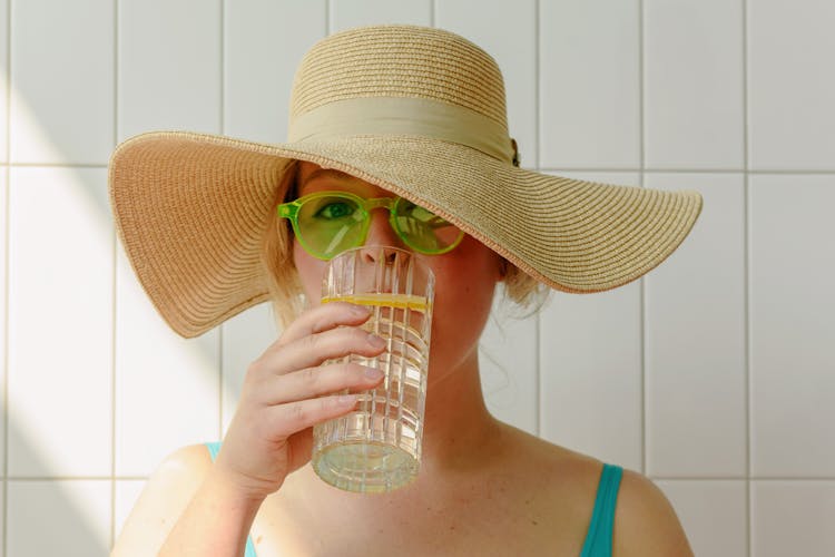 Close-Up Photo Of Woman Drinking A Glass Of Water With Lemon