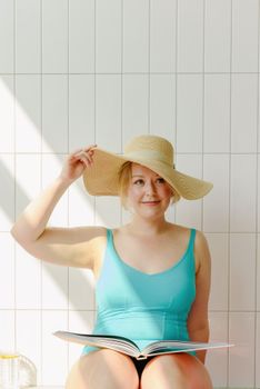 A woman in a swimsuit and sun hat enjoying a relaxing moment indoors.