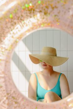 A woman in a sun hat and swimsuit enjoys a relaxed moment on a sunny summer day.