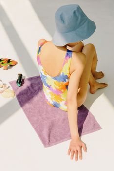 Person in colorful swimsuit and hat relaxing with summer accessories.