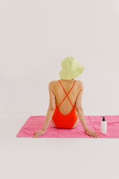 Woman in stylish swimwear and bucket hat sitting indoors, showcasing summer fashion.