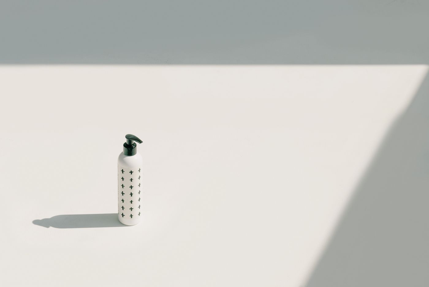 Pump bottle casting a long shadow on a bright neutral surface — photo by Ksenia Chernaya on Pexels