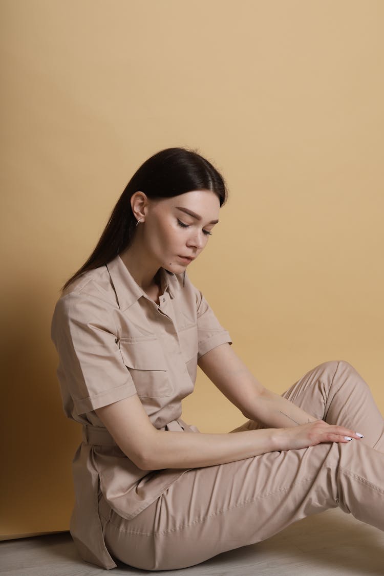 A Woman In A Khaki Outfit Sitting On The Floor