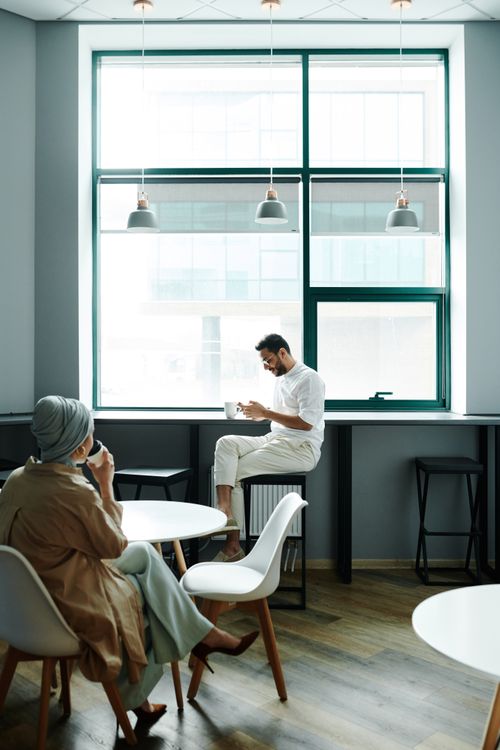 Free A relaxed setting in a modern café with two adults enjoying coffee by the window. Stock Photo