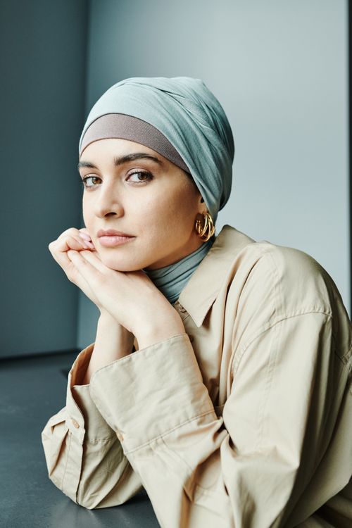 Free Elegant portrait of a young woman with a hijab, wearing a beige outfit, indoors. Stock Photo