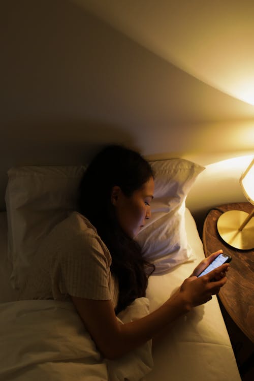 Free 
A Woman Using Her Smartphone while in Bed Stock Photo