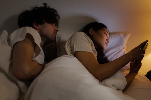 Free Man Reading Woman's Messages while on Bed Stock Photo