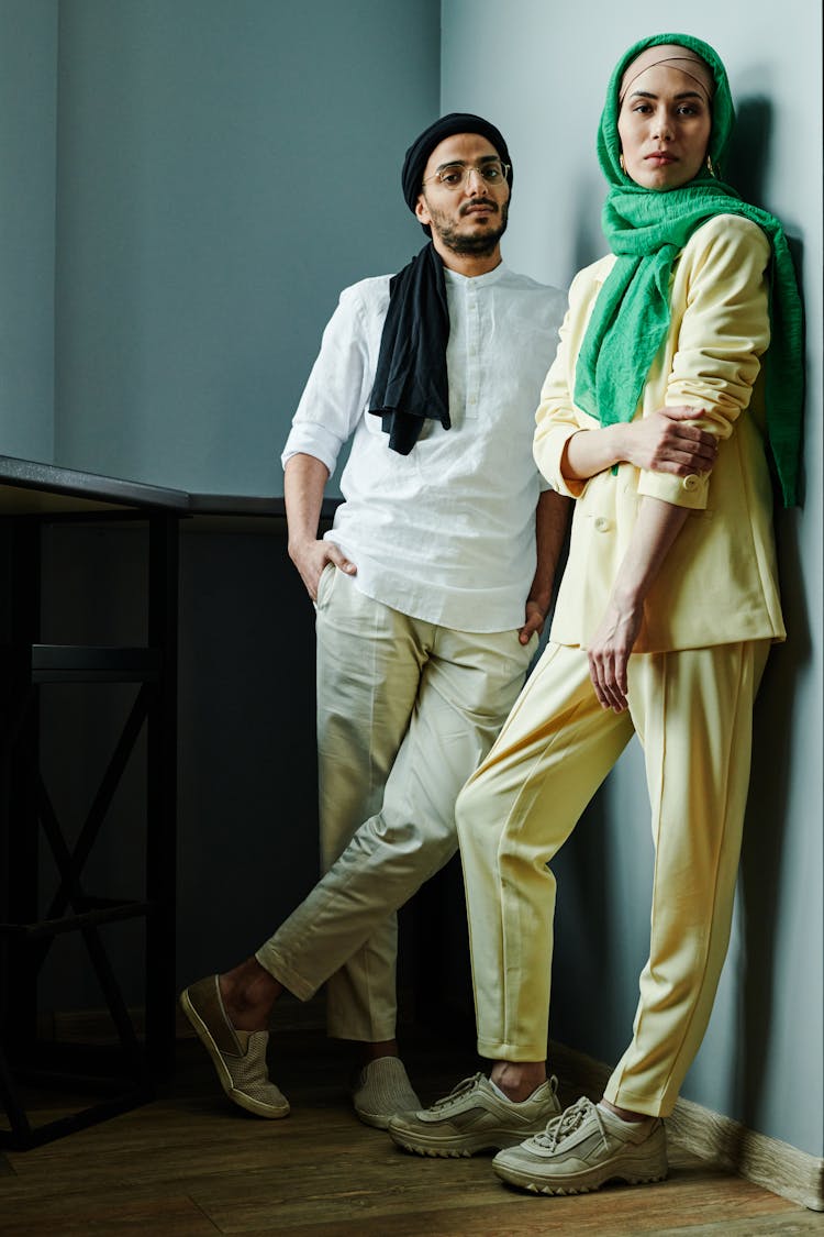 A Man And Woman Wearing Headscarf While Leaning On The Wall