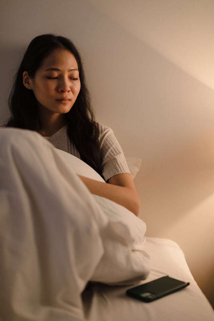 A Woman Crying While Sitting On The Bed