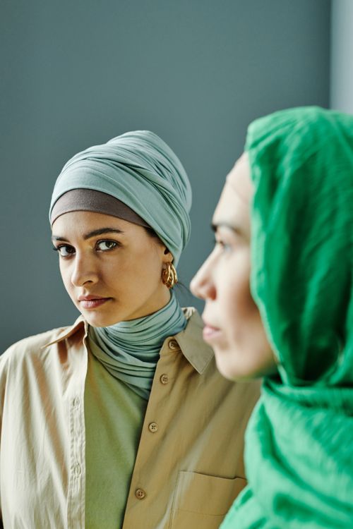 Free Portrait of two women wearing fashionable headscarves in a studio setting, exuding modern elegance. Stock Photo