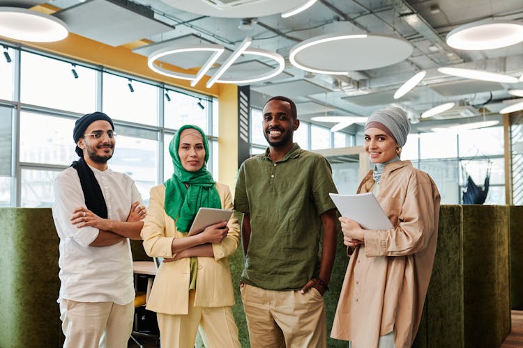 A Group Of People Smiling While Standing Inside The Office