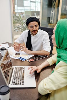 Business professionals discussing strategies in a modern workspace with a laptop and documents.