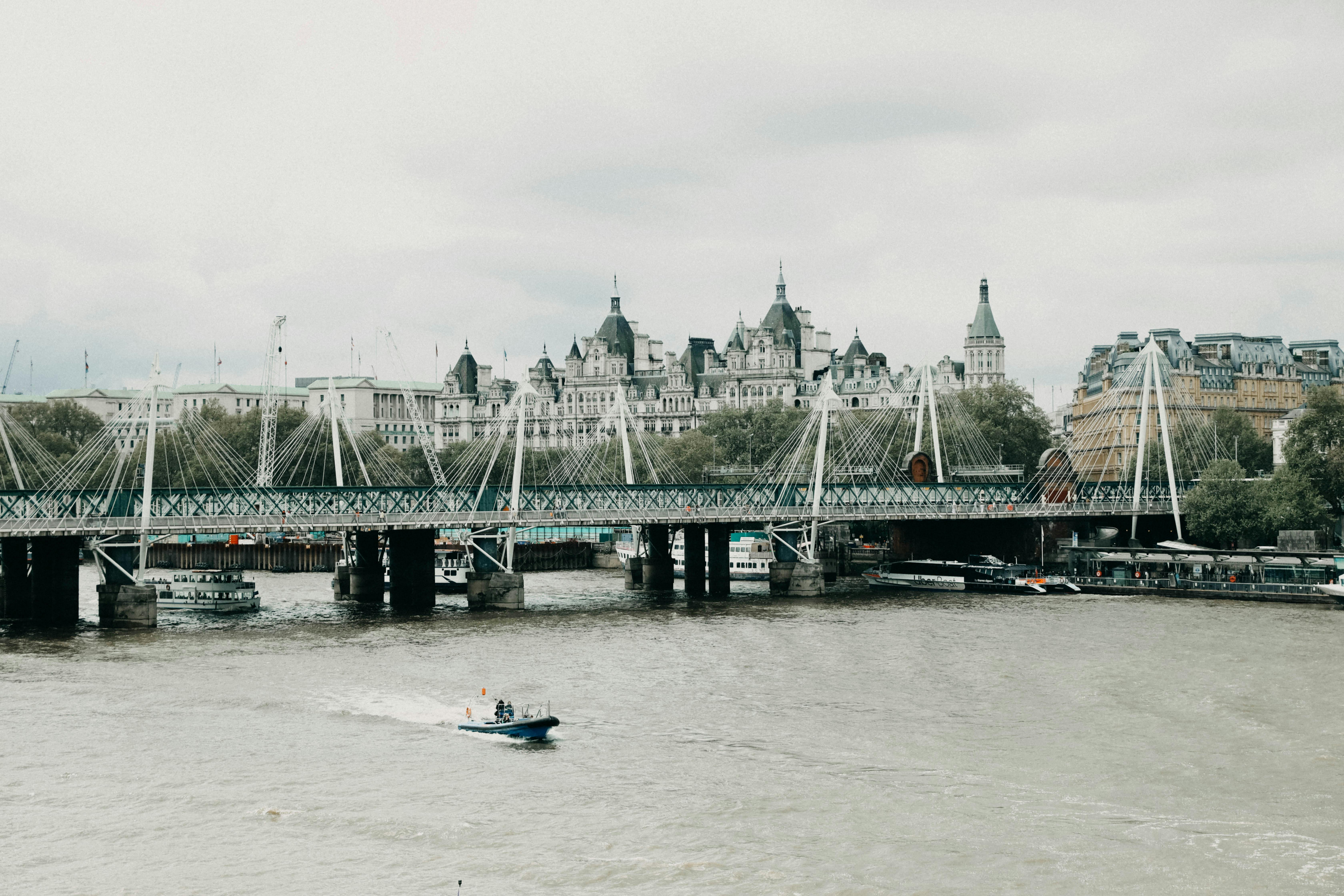 Scenic view of London with the River Thames and prominent structures under a cloudy sky.