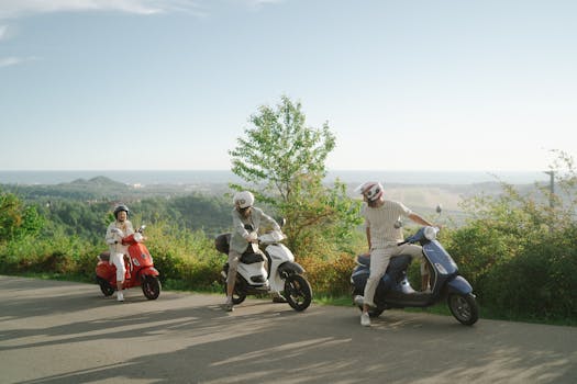 Three friends riding motor scooters on a country road, enjoying a sunny day with scenic views.