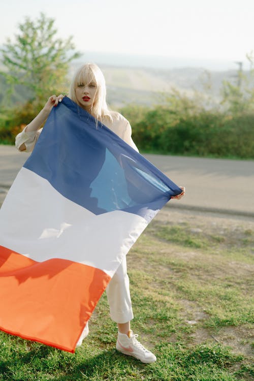 A Woman Standing on the Road while Holding a Flag