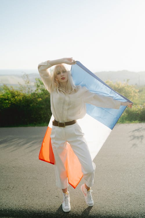 Woman in White Long Sleeves and Pants Holding a Flag of France