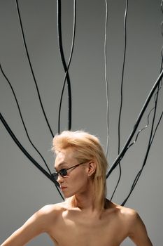 An artistic portrait featuring a person with cables against a plain background.