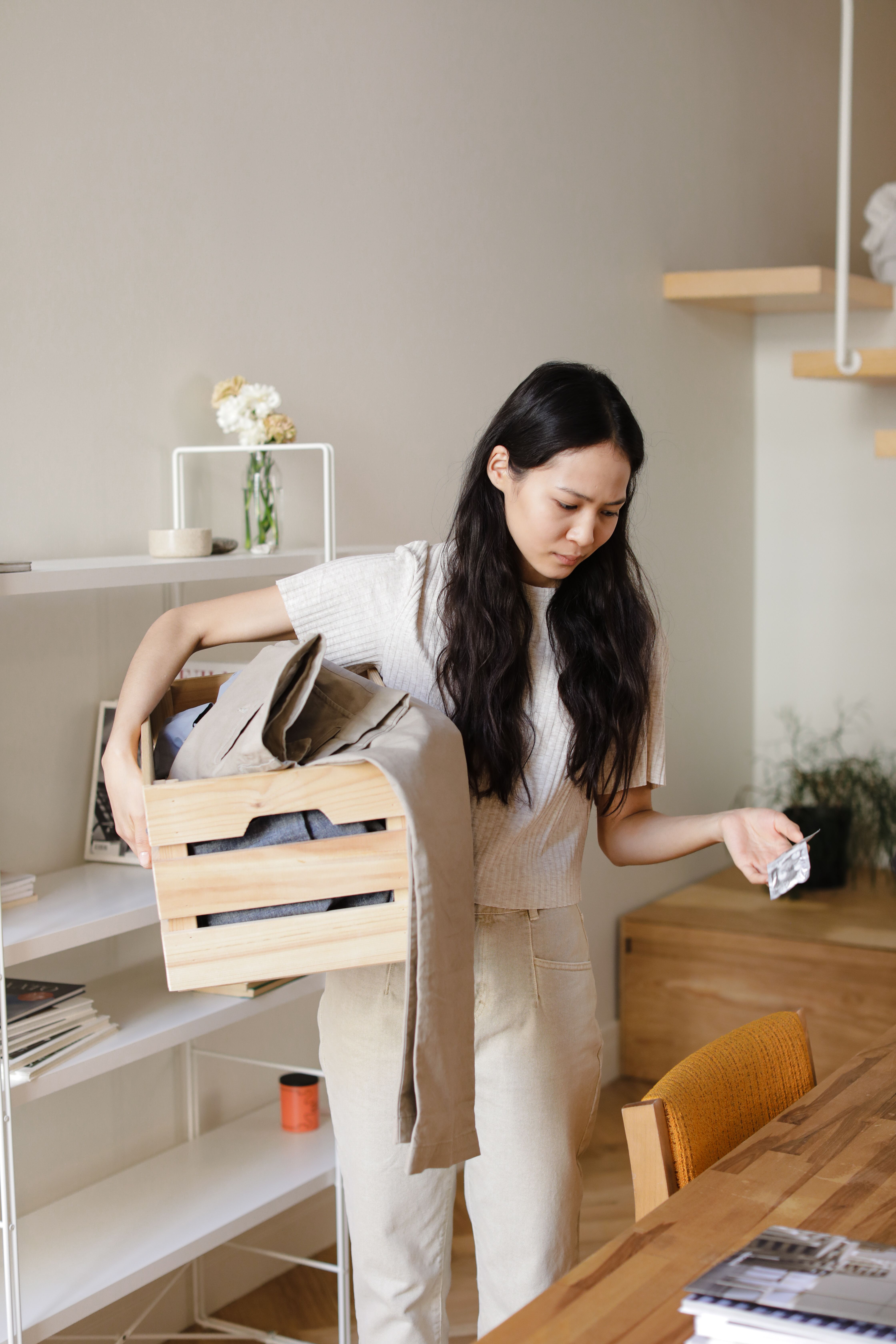 Woman organizing her home using a wooden crate for storage solutions.