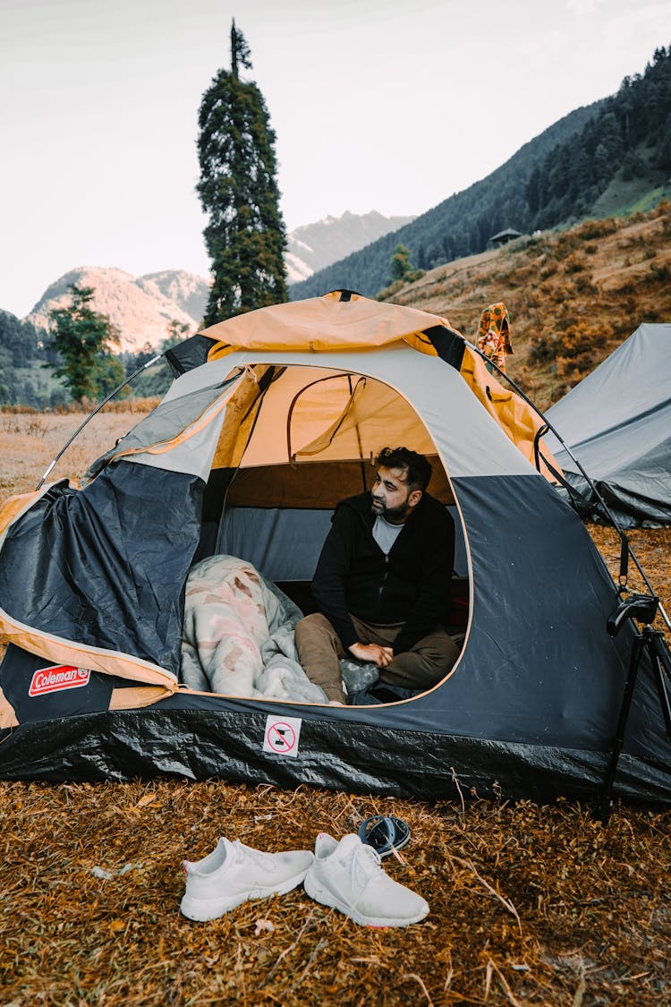 A Man In Black Jacket Sitting Inside The Tent