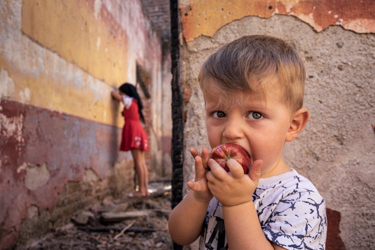 Boy Eating An Apple While Playing Hide And Seek 