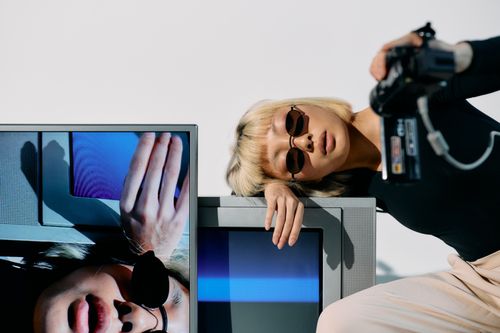 Free Stylish portrait featuring a fashion model with CRT monitors and a vintage camera. Stock Photo