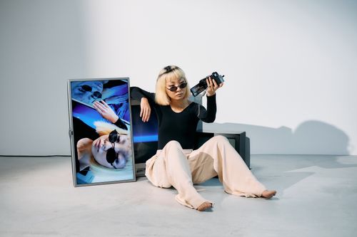 Free Fashion model poses with sunglasses and vintage CRT monitor, creating an edgy studio shoot. Stock Photo