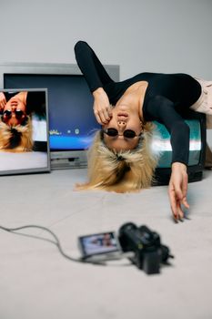 Stylish model posing with retro TVs and camera in an artistic fashion shoot.