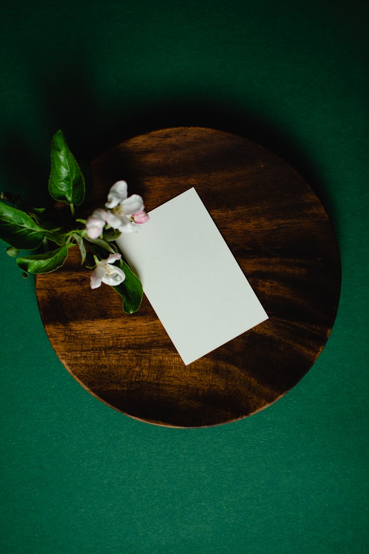 
A Blank White Paper And Flowers On A Round Wooden Board