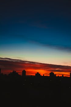 Scenic view of house silhouettes under red and blue cloudy sky in town at night