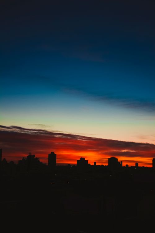 Free Scenic view of house silhouettes under red and blue cloudy sky in town at night Stock Photo