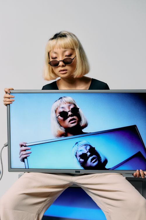 Free Stylish fashion model in sunglasses holding a monitor with artistic screen repetition. Stock Photo