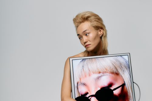 Free Fashion model with edgy hairstyle posing with showcased screen in studio. Stock Photo