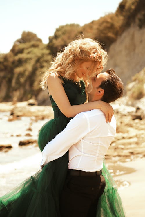 Free Man Carrying the Blonde Woman in Green Gown Stock Photo