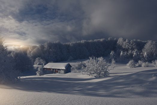 Serene winter landscape with a snow-covered cabin in Inegöl, Turkey at sunrise.