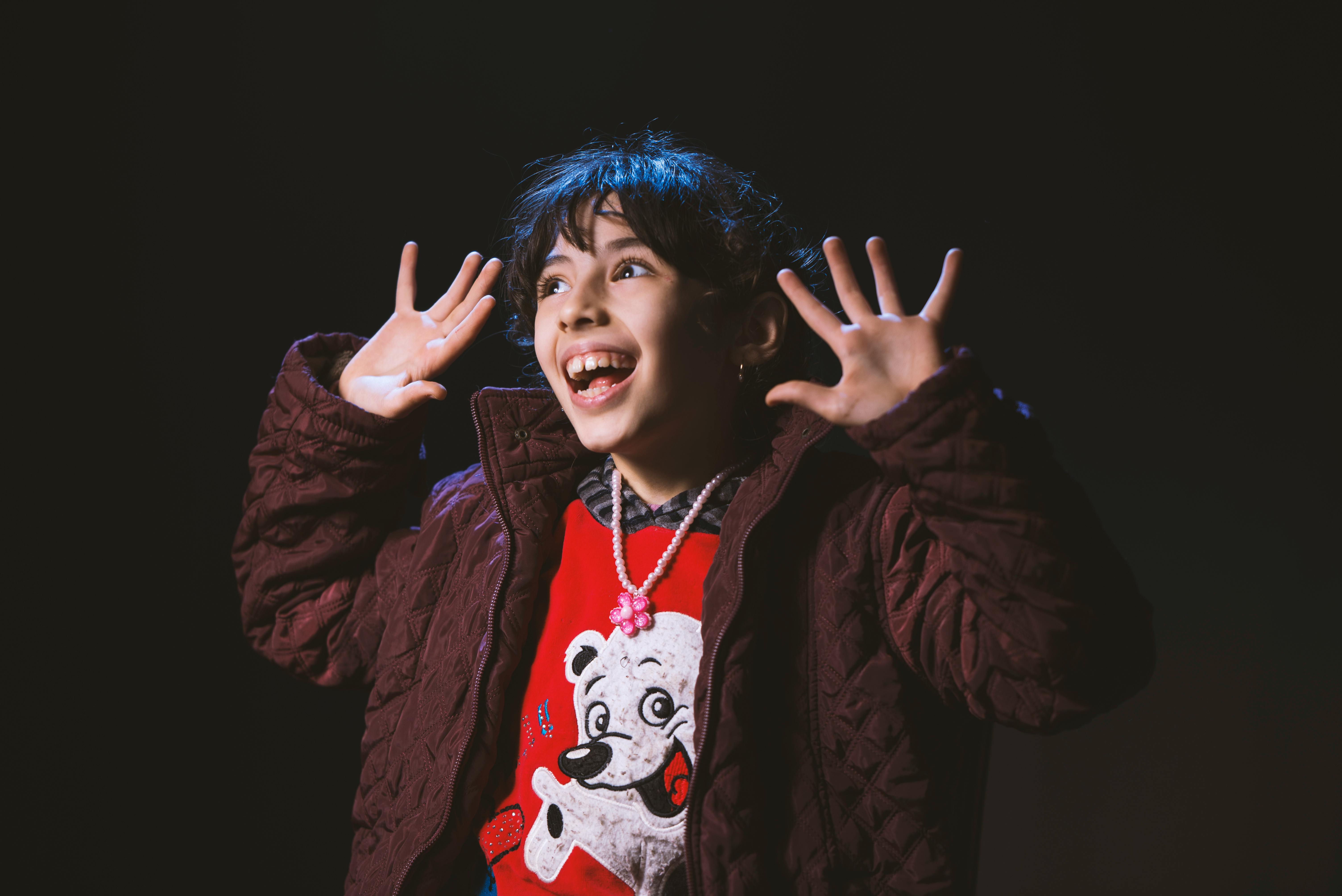 孩子穿着冬季夹克，戴着项链，笑容满面地表达喜悦