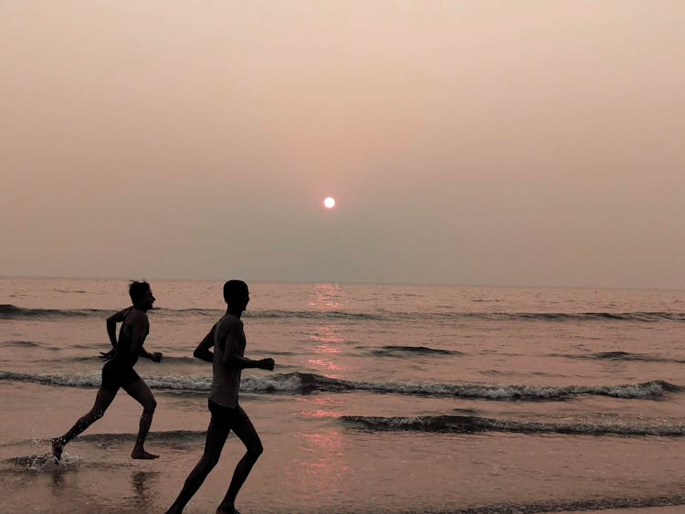 Silhouette Of People Running In The Beach