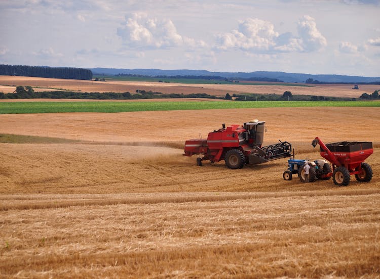 Farmers Using Tractors On A Farm Field