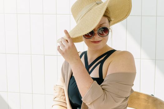 Chic woman wearing a large sun hat and round sunglasses exudes summer style.