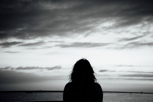 A Silhouette of a Woman Looking at the Sea