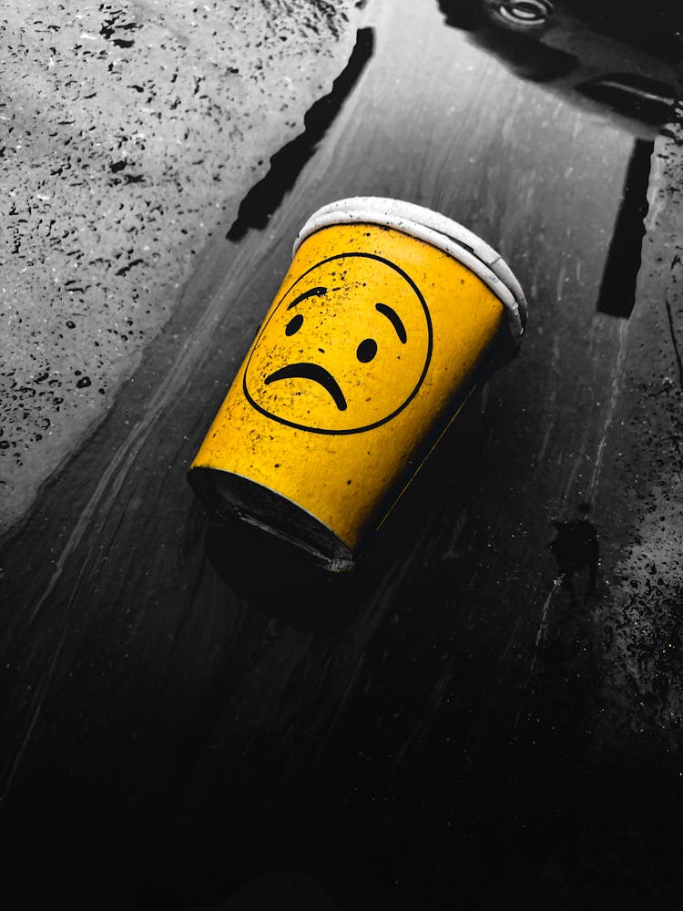 Plastic Cup With Sad Emoji On Ground