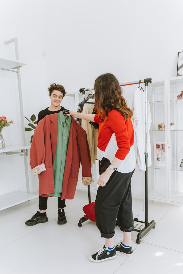 A Woman Showing The Clothes She Is Holding To The Man Standing In Front Of Her